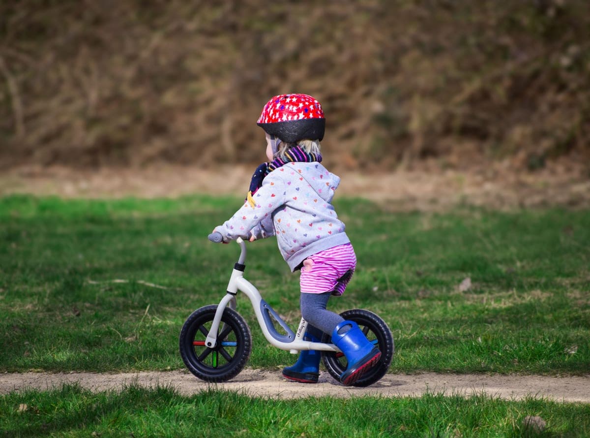 Young child in a helmet riding a balance bike