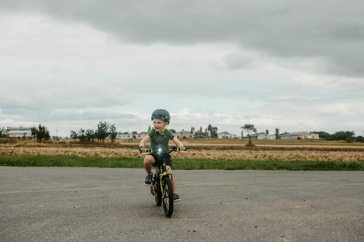 Child in a helmet riding a pedal bike on a road