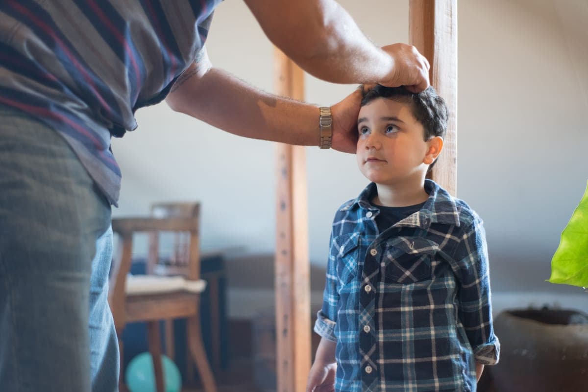 A parent measuring a child's height against a wall