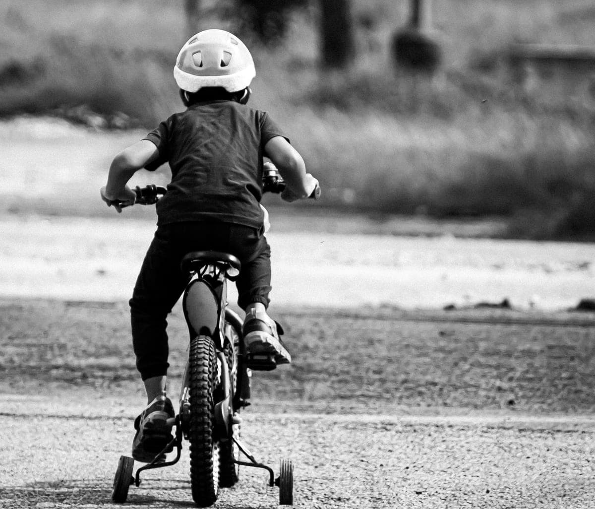 A child riding a bike fitted with training wheels